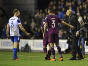 Manchester City manager Josep Guardiola, right, discusses with Wigan's Max Power, left, during the English FA Cup fifth round soccer match between Wigan Athletic and Manchester City at The DW Stadium, Wigan, England, Monday, Feb. 19, 2018.