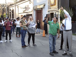 People stands in the street as an earthquake shakes Mexico City, Friday, Feb. 16, 2018. A powerful 7.2-magnitude earthquake has shaken south and central Mexico, causing people to flee buildings and office towers in the country's capital, and setting off quake alert systems.
