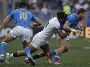 England's Anthony Watson, centre tackles Italy's Matteo Minozz, right, during the Six Nations rugby union international match between Italy and England at the Olympic Stadium, in Rome, Italy, Sunday, Feb. 4, 2018.