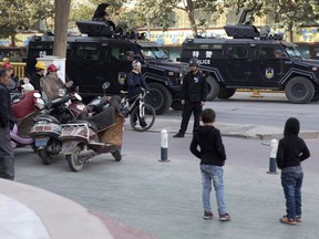 FILE - In this Nov. 5, 2017, file photo, residents watch a convoy of security personnel and armored vehicles in a show of force through central Kashgar in western China's Xinjiang region. Human Rights Watch says it has found new evidence that authorities in one of China's most repressive regions are sweeping up citizens' personal information in a stark example of how modern big-data technology can be applied to policing, and potentially abused.