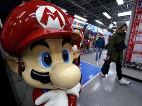 A Super Mario figure greets shoppers at an electronics store in Tokyo, Wednesday, Jan. 31, 2018. Japanese video-game maker Nintendo says its net profit jumped 31 percent in April-December from a year earlier, helped by the popularity of its Switch hybrid game machine.