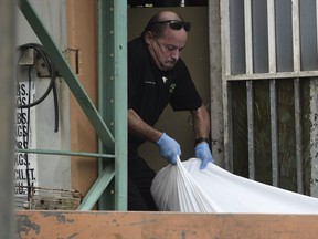 FILE - In this Jan. 11, 2018 file photo, a forensic worker lifts a body at a crime scene in San Juan, Puerto Rico. The first month of 2018 was one of Puerto Rico's deadliest months in recent years as the U.S. territory struggles with a surge in violent crime and growing discontent among tens of thousands of police officers.