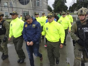 FILE - This undated photo released by Colombia's National Police show officers escorting a man who police identify as Ecuadorean drug trafficker Washington Edison Prado after his April 2017 arrest on an indictment by a Florida federal court. Colombia's chief prosecutor's office said Saturday, Feb. 24. 2018, that it has extradited Prado to the United States. (Colombia National Police via AP, File)