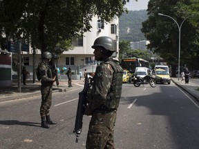 A soldier stops traffic for an armored vehicle to park on a street, before a meeting with Brazil's President Michel Temer and local authorities about the implementation of a decree that has placed the military in charge of Rio's state security, at the Guanabara palace in Rio de Janeiro, Brazil, Saturday, Feb. 17, 2018.