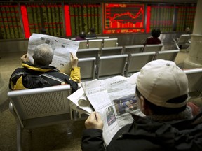 Investors read newspapers as they monitor stock prices at a brokerage house in Beijing, Tuesday, Feb. 6, 2018. Shares tumbled in Asia on Tuesday after a wild day for U.S. markets that resulted in the biggest drop in the Dow Jones industrial average in six and a half years.
