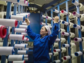 In this Feb. 22, 2018 photo, a woman works with spools of thread in a textile company in Hai'an county in eastern China's Jiangsu province. A report released Wednesday, Feb. 28, 2018 says that China's manufacturing activity weakened to its lowest level in 19 months as the extended Lunar New Year holiday has left the month with fewer work days. (Chinatopix via AP)