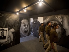 In this Friday, Feb. 9, 2018, photo, policewomen look at the art project of Subba Ghosh "THE FLOW" during India Art in New Delhi, India. Human displacement, the suffering of refugees and the notion of identity dominated the 2018 India Art Fair, an important platform for contemporary artists that provides a carefully curated glimpse into the Asian art scene through the years.