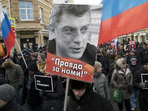 A man carries a portrait of slain opposition leader Boris Nemtsov during a march marking the three-year anniversary of his killing, in Moscow, Russia, Sunday, Feb. 25, 2018. Thousands of Russians took to the streets of downtown Moscow to mark three years since Nemtsov was gunned down outside the Kremlin.