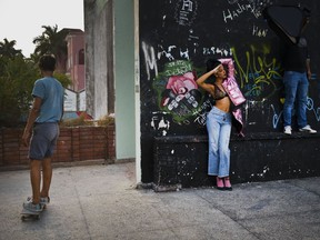 In this Jan. 11, 2018 photo, a young model and a member of the lighting crew use as their backdrop an abandoned gym that was converted into space for skateboarders, the day of the space's inauguration inside the Educational complex Ciudad Libertad, a former military barracks that the late Fidel Castro turned into a school complex after the revolution in Havana, Cuba. Cuba's official sports establishment once took a dim view of skaters, but over the past 15 years it has tolerated, and occasionally encouraged, skateboarding.