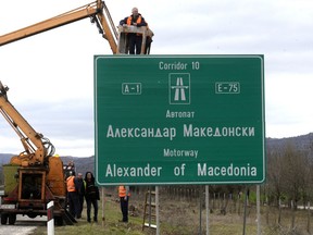 Workers prepare to remove a road sign that reads ''Alexander of Macedonia'' on the highway linking the capital Skopje with northern Greece, on Wednesday, Feb. 21, 2018. Macedonian authorities have begun replacing road signs on the country's main highway named by the previous government after the ancient warrior king Alexander the Great, in a goodwill gesture toward neighboring Greece.