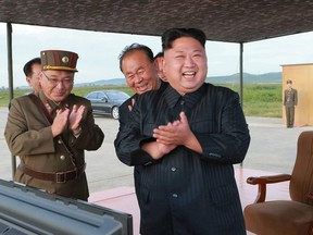 In this undated file photo distributed on Sept. 16, 2017, by the North Korean government, North Korean leader Kim Jong Un, right, celebrates what was said to be the test launch of an intermediate range Hwasong-12 missile at an undisclosed location in North Korea.