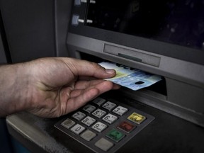 A man withdraws cash from an ATM machine in Athens on July 19, 2016.