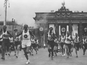 A relay runner carries the Olympic Flame through the Brandenburg Gate on his way to the Reichssportfeld Olympic Stadium before the start of the 1936 Olympic Games in Berlin.