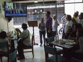 Diners watch as Peru's President Pedro Pablo Kuczynski delivers a nationwide televised address announcing that he has offered his resignation to Congress, in Lima, Peru, Wednesday, March 21, 2018. Kuczynski offered up his resignation ahead of an impeachment vote scheduled for Thursday, citing unjustified attacks by opponents that made it impossible to govern.