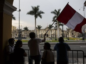 Roger Benitez waves a Peruvian flag near the House of Pizarro government palace, as an action against President Pedro Pablo Kuczynski in Lima, Peru, Wednesday, March 21, 2018. Embattled Kuczynski offered his resignation Wednesday ahead of an impeachment vote, seeking to put an end to a fast-moving political drama playing out just three weeks before the Andean nation is set to host U.S. President Donald Trump for a regional summit.
