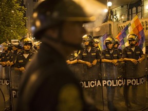 Police in riot gear hold their ground during a demonstration against the country's political class, a day after the resignation of Peru's President Pedro Pablo Kuczynski, in Lima, Peru, Thursday, March 22, 2018. Peru's congress is gearing up to consider whether or not to accept Kuczynski's resignation following the release of several videos appearing to show allies offering state contracts in exchange for votes against his pending impeachment.