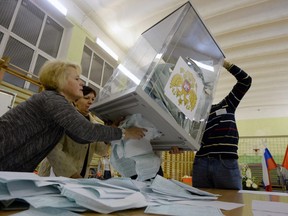 Members of a local election commission empty a ballot box as they start counting votes during Russia's presidential election in Saint Petersburg on March 18, 2018.