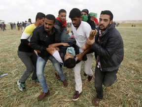 Palestinian protesters evacuate a wounded youth during clashes with Israeli troops along the Gaza Strip border with Israel, east of Khan Younis, Gaza Strip, Friday, March 30, 2018.