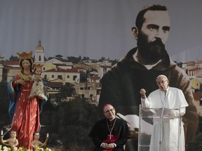 Pope Francis speaks to faithful in Pietrelcina, southern Italy, the birthplace of St. Padre Pio, Saturday, March 17, 2018, during a one-day pastoral visit to Pietralcina and San Giovanni Rotondo. Saint Pio, pictured in the background, who is widely venerated in Italy and abroad is famous for bearing the stigmata, the wounds of crucified Jesus. At center, Benevento's Archbishop Felice Accrocca listens,