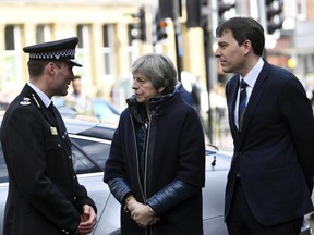 Britain's Prime Minister Theresa May, centre, is briefed by members of the police as she views the area where former Russian double agent Sergei Skripal and his daughter were found critically ill, in Salisbury, England, Thursday, March 15, 2018.  May on Wednesday expelled 23 Russian diplomats, severed high-level contacts and vowed both open and covert action following the incident.
