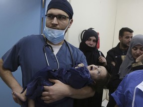 In this March 5, 2018 photo, the family of one-year-old Syrian refugee Eman Zatima watch as she is carried by a Jordanian doctor to the operating room, at a hospital in Amman, Jordan. Eman, who has a heart defect, received a life-saving pro bono surgery from doctors sent by the Vatican's Bambino Gesu Hospital. The infant is one of the few lucky Syrian refugees with severe medical conditions to get the needed treatment.