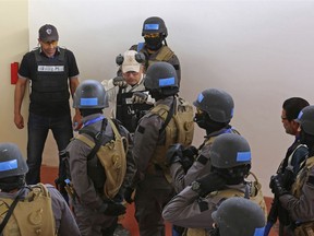 In this Sunday, March 18, 2018 photo, an instructor speaks to members of a Tunisian police commando unit during a drill at the Jordan Gendarmerie Training Academy, in al-Swaqa, about 44 miles (70 km) south of Amman, Jordan. The U.S.-funded center, which formally opens Thursday, will conduct counter-terrorism training for law enforcement agencies from a pool of 56 eligible partner countries.