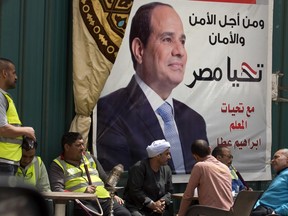People chat and smoke traditional water pipes under an election campaign banner for Egyptian President Abdel-Fattah el-Sissi, with Arabic that reads, "for the sake of the nation security", in Cairo, Egypt, Saturday, March 24, 2018. President Abdel-Fattah el-Sissi, the general-turned-president, will stand for re-election next week against Moussa, a little-known politician who has made no effort to challenge him.