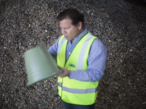 In this Tuesday, March 13, 2018 photo, Jack Tato Bigio co-Founder and Chief Executive at UBQ, holds a recycled plastic bucket next to a pile of dried and shredded garbage at the UBQ factory in Kibbutz Zeelim. Israeli start-up UBQ says its innovative method to convert garbage into plastics, five years in the making, will revolutionize waste management worldwide and make landfills obsolete.