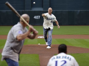 Former Arizona Diamondbacks pitcher Andy Benes (40) throws the ceremonial first pitch to former Colorado Rockies' Mike Lansing as former Diamondbacks catcher Jorge Fabregas (12) catches prior to a baseball game Saturday, March 31, 2018, in Phoenix. The pitch re-created the first pitch delivered to the first batter in the first-ever Diamondbacks game on March 31, 1998.