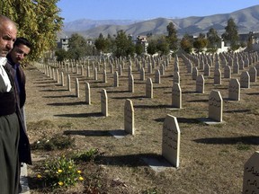 FILE - In this Dec. 7, 2006 file photo, men stand at a graveyard where the dead of 1988 gas attack on Halabja, Iraq, Iraq's Kurdish region has commemorated the 30th anniversary of Saddam Hussein's 1988 gas attack in the northeastern Kurdish town of Halabja that killed 5,000 people.