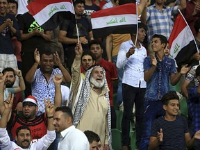 FILE - In this Sept. 9, 2017 file photo, soccer fans wave national flags during a friendly match, in Basra, Iraq. An Iraq-Qatar match, part of a friendly soccer tournament this week with Syria and Qatar, is to start Wednesday, March 21, 2018, in Basra. While friendly matches have been allowed for some time, last week FIFA lifted a three-decade ban on international competitions for the Iraqi cities of Basra, Karbala and Irbil, considered to be the safest in Iraq -- but not Baghdad, which still sees militant attacks.