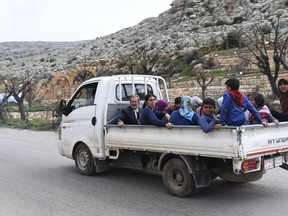 This photo released on Wednesday, March 7, 2018 by the Syrian official news agency SANA, shows Kurds in the back of a truck as they flee from their village where Turkish forces and Syrian rebels battle against Kurdish fighters, in Afrin, northern Syria. Turkey's foreign minister says his government hopes that a cross-border military offensive in a Syrian Kurdish-held enclave will end before May. (SANA via AP)