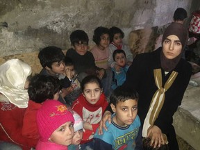 This Sunday, March 11, 2018 photo, provided by Deana Lynn, from Detroit, Michigan, shows her, with her kids and other Syrian children at a shelter where they hide from Russian and Syrian government forces airstrikes, in eastern Ghouta, a suburb of the Syrian capital Damascus. Lynn is calling on President Donald Trump to put more pressure on Russia to "stop bombing us" amid an air and ground assault by government forces that has killed more than 1,000 people over the past three weeks. Lynn and her family are among nearly 400,000 people who are trapped in eastern Ghouta. (Deana Lynn via AP)