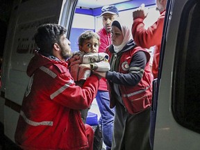 This photo released Tuesday March 13, 2018 by the Syrian Red Crescent, shows members of the Syrian Red Crescent carrying a boy who fled with his family from the fighting between Syrian government forces and rebels, in eastern Ghouta, a suburb of Damascus, Syria. Russian news agencies said at least 100 civilians have been evacuated from eastern Ghouta including 20 women and children. The Syrian government and the Russian military have set up a corridor outside eastern Ghouta to arrange the evacuation from the area which is home to some 400,000 people. (Syrian Red Crescent via AP)