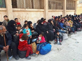 This photo released by the Syrian official news agency SANA, shows Syrian civilians, who fled fighting between the Syrian government forces and rebels, at an army checkpoint, in eastern Ghouta, a suburb of Damascus, Syria, Tuesday March 13, 2018. The Syrian government and the Russian military have set up a corridor outside eastern Ghouta to arrange the evacuation from the area which is home to some 400,000 people. (SANA via AP)