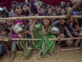 FILE - In this Saturday, Oct. 21, 2017, file photo, Rohingya Muslim children wait for food handouts distributed by a Turkish aid agency at Thaingkhali refugee camp, Bangladesh. Myanmar's government has rejected two reports presented to the U.N. Human Rights Council that concluded it committed extreme human rights violations, probably amounting to crimes under international law, in its repression of several minority groups.