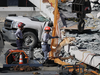 A rescue dog and its handler search for possible survivors at the scene of a collapsed pedestrian bridge in Miami, Florida, on March 15, 2018.