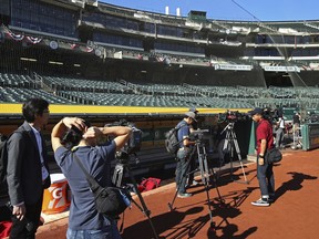 Members of the media begin to surround the Los Angeles Angels dugout three hours before game time as they await the arrival of Shohei Ohtani prior to a baseball game against the Oakland Athletics on Thursday, March 29, 2018, in Oakland, Calif.
