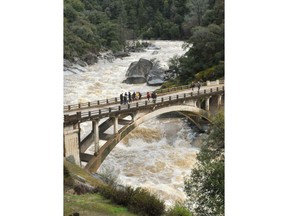 Spectators gather on the historic Highway 49 bridge over the South Fork Yuba River Thursday, March 22, 2018 to witness an intense amount of rain and snowmelt runoff rush downstream during Thursday's atmospheric river event.