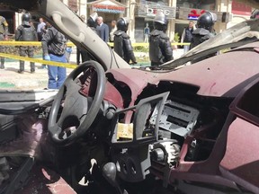 Security members stand guard as investigators search the area after a bomb placed under a nearby car exploded Saturday, March 24, 2018 in Alexandria, Egypt, as the city security chief's convoy passed by, killing at least one policeman and wounding four others, the Interior Ministry said. Local media reports said Gen. Mostafa al-Nimr survived the explosion and he was seen on a local TV channel in good condition while inspecting the area of the blast shortly after it took place. No group immediately claimed responsibility for the explosion, which happened in the vicinity of a police station in the central district of Roshdi.