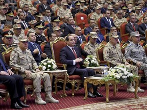 In this photo released by the Egyptian Presidency, Egyptian President Abdel-Fattah el-Sissi, center, attends a conference commemorating the country's martyrs, in Cairo, Egypt, Thursday, March 15, 2018. Up for re-election in less than two weeks, Egypt's president on Thursday took center stage at a televised ceremony declaring his readiness to personally join the battle against militants and decorating soldiers and families of fallen ones.