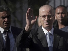 FILE - In this Oct. 3, 2017 file photo, Palestinian Prime Minister Rami Hamdallah, center, waves to journalists as he arrives to head a Cabinet meeting, in Gaza City. On Tuesday March 13, 2018 an explosion struck the convoy of the Hamdallah during a rare visit to Gaza, in what his Fatah party called an assassination attempt it blamed on Gaza militants. Hamdallah was unharmed and went on to inaugurate a long-awaited sewage plant project in the northern part of the strip.
