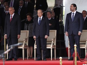 FILE - In this Nov. 22, 2017 file photo, Lebanese President Michel Aoun, center, Lebanese Prime Minister Saad Hariri, right, and Lebanese Parliament Speaker Nabih Berri, left, attend a military parade in Beirut, Lebanon. Egyptians go to the polls next week in what is essentially a one-candidate election -- but almost nowhere has democracy taken hold in the Arab world. With a parliamentary system and regular presidential elections, Lebanon has trappings of a democracy, but politics are dominated by former warlords and family dynasties that have long used the country's sectarian-based power-sharing system to perpetuate corruption and nepotism.