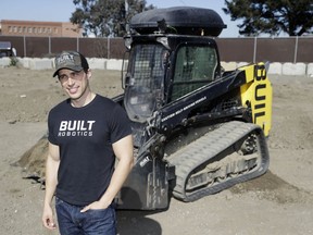 Built Robotics CEO Noah Ready-Campbell poses for a picture in front of the company's autonomous track loader Wednesday, Feb. 21, 2018, in San Francisco. Backed by Silicon Valley money, tech startups are developing self-driving bulldozers, drones to inspect work sites and robot bricklayers that can lay bricks faster than human and work without lunch breaks.