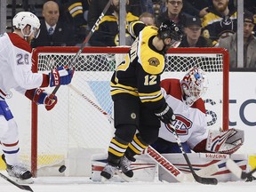The puck deflects wide of the net behind Boston Bruins' Brian Gionta (12) and Montreal Canadiens' Antti Niemi, right, during the first period of an NHL hockey game in Boston, Saturday, March 3, 2018. (/)