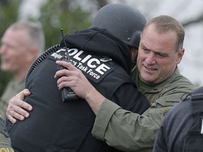 Pomona Police officers hug after arresting the stand-off suspect in an apartment Saturday, March 10, 2018, in Pomona, Calif. The gunman who shot two California police officers, killing one of them, was arrested Saturday after barricading himself in an apartment and holding a SWAT team at bay for more than 15 hours, authorities said.