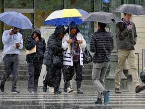 Pedestrians make their way across a street in the pouring rain in downtown Los Angeles on Wednesday, March 21, 2018. The storm came ashore on the central coast and spread south into the Los Angeles region and north through San Francisco Bay, fed by a long plume of subtropical moisture called an atmospheric river.