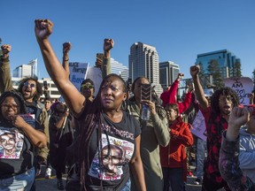 Veronica Curry raises her fist with other supporters of the Black Lives Matter movement during a rally on Interstate 5 in Sacramento, Calif., Thursday, March 22, 2018. Protesters decrying this week's fatal shooting of an unarmed black man marched from Sacramento City Hall and onto the nearby freeway Thursday, disrupting rush hour traffic and holding signs with messages like "Sac PD: Stop killing us!"