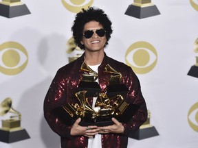 FILE - In this Jan. 28, 2018 file photo Bruno Mars poses with his awards at the 60th annual Grammy Awards in New York. The Weeknd, Bruno Mars, Jack White and Arctic Monkeys will headline this year's Lollapalooza music festival in Chicago. Travis Scott, The National, Vampire Weekend and Odesza also were among the headliners announced Wednesday, March 21, on Lollapalooza's website.