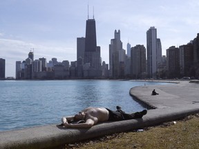 FILE - In this Feb. 27, 2018 file photo, Johnny Perez suns himself in springlike temperatures along Lake Michigan in Chicago. Congressional leaders are rejecting President Donald Trump's effort to kill or sharply cut funding of programs to protect and restore some of the nation's prized waters, such as the Great Lakes and Chesapeake Bay.